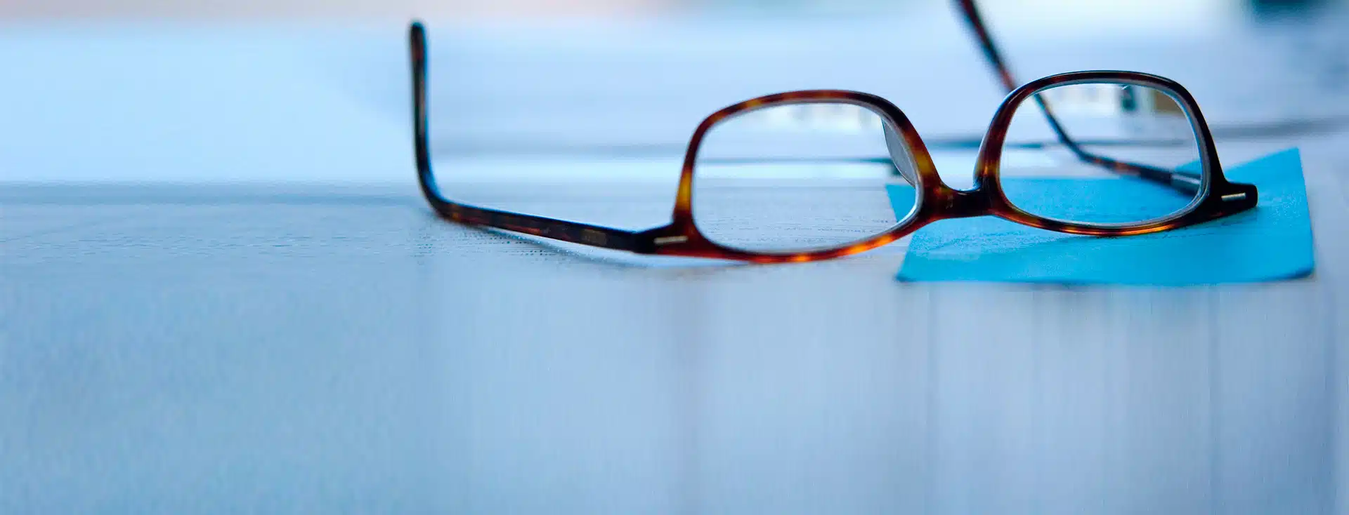 A pair of glasses lies beside a page of notes