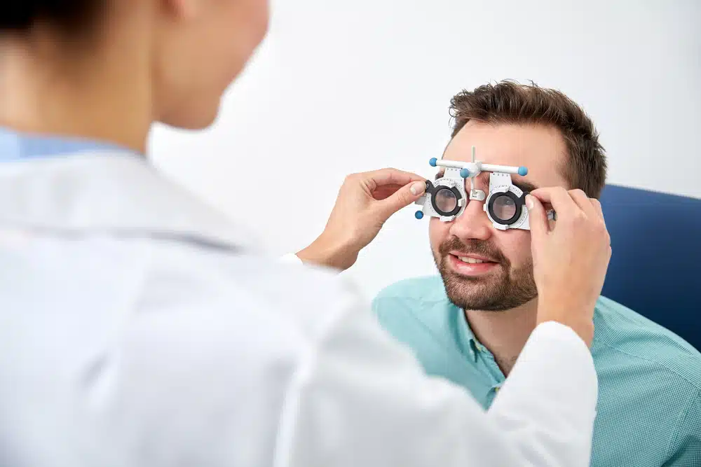 optometrist with trial frame checking patient vision at eye clinic
