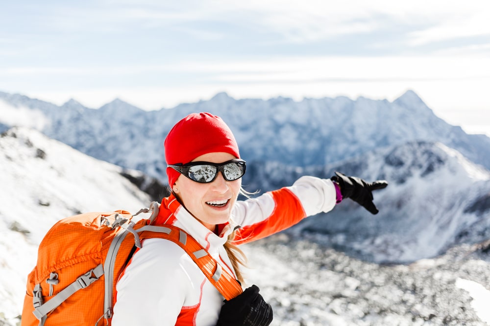 woman wearing sunglasses while hiking in the winter