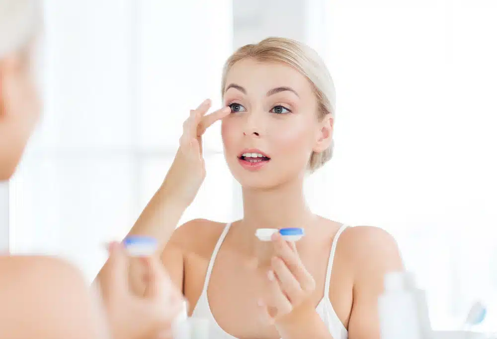 young women putting on contact lenses