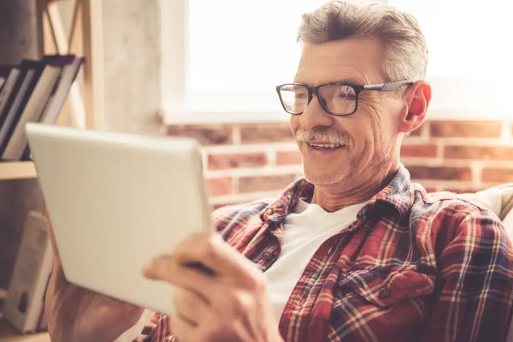 Older man wearing transition lenses using a tablet