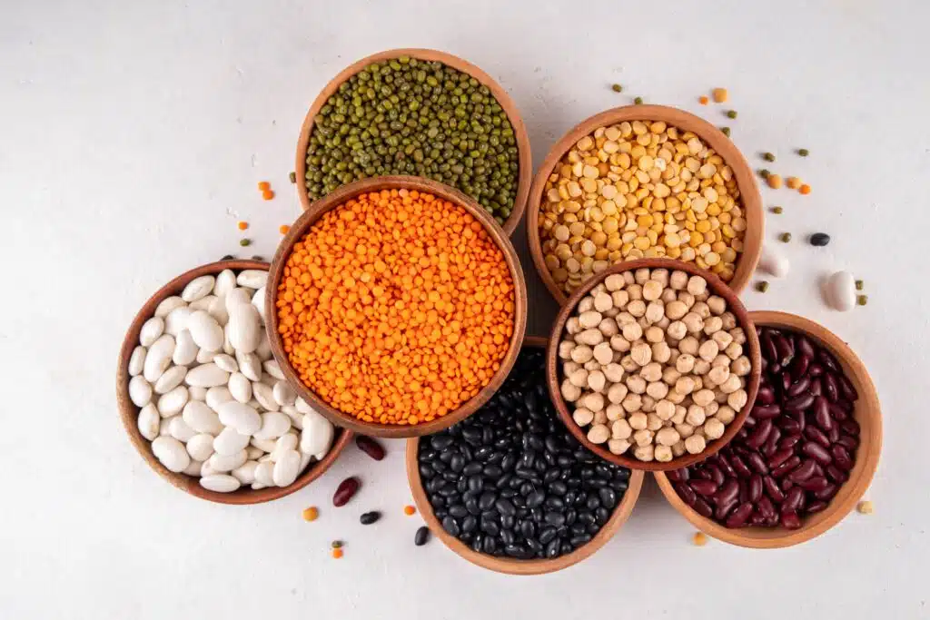 Assorted beans, lentils, and legumes in bowls, arranged in a vibrant, healthy display.
