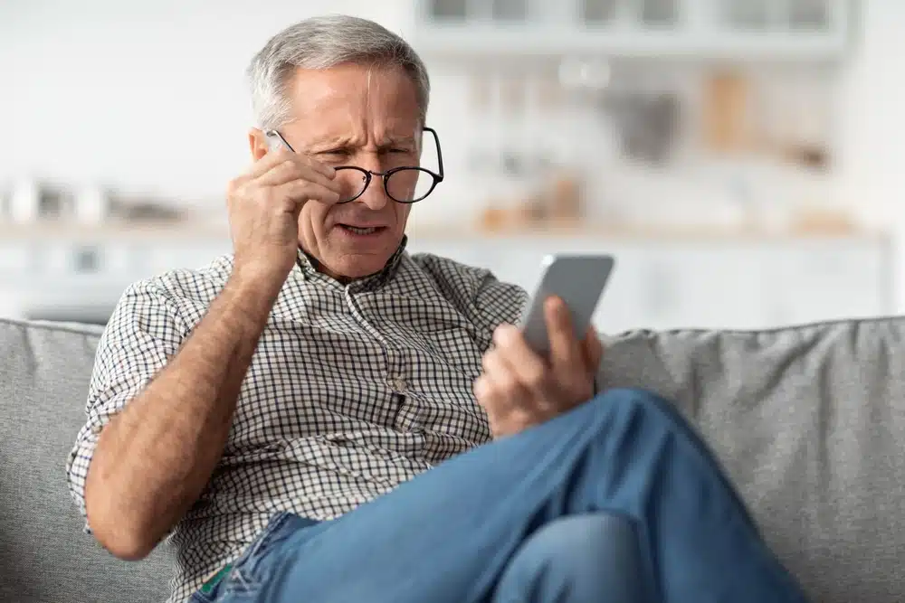 Older adult adjusting his glasses to see close.